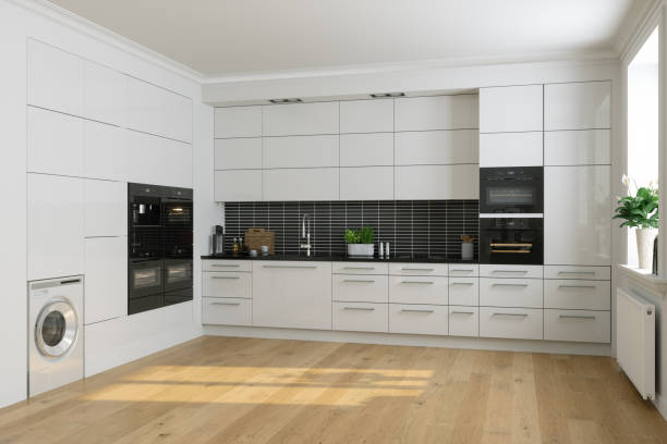 Современный дизайн интерьера белой кухни со встроенной техникой и деревянным полом.